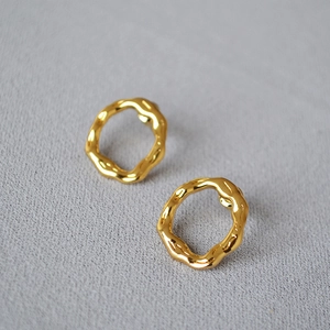 Macro view of gold plated irregular ripple hoop earrings with a polished mirror finish