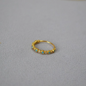 Macro view of gold-plated brass ring with turquoise and clear zircon bezel settings
