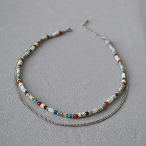 Detail of double-layer beaded necklace with colorful stones and silver flat snake chain