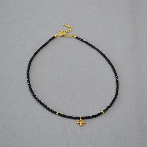 Dettaglio della collana di spinello nero con pendente a croce dorata e chiusura a moschettone