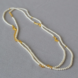 Detailed macro view of long pearl necklace with elegant gold metal chain accents