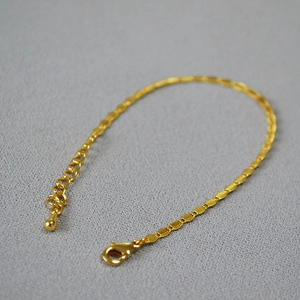 Macro shot of gold-plated brass chain with adjustable lobster clasp and droplet charm