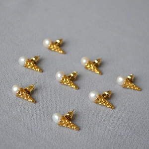 Detail of ice cream cone earrings with round white pearls and golden textured metal base