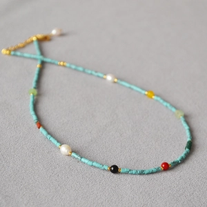 Close-up of vintage beaded necklace with turquoise tubes, white pearls and gold clasp