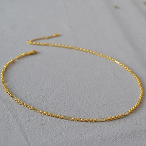 Close-up of gold-plated brass chain with interlocking circular links and lobster clasp
