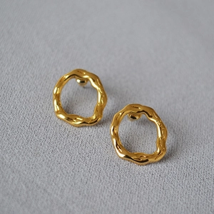 Macro detail of irregular gold-plated earrings with molten lava texture and 925 silver posts