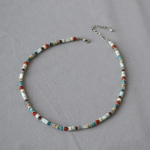 Detail of colorful beaded necklace showing silver lobster clasp and extension chain