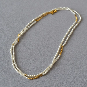 Detail of double-layer necklace with glossy white pearls and golden lobster clasp