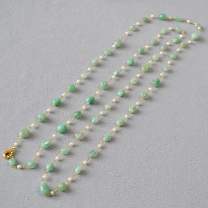Detail of handmade long necklace with green stones, white pearls, and gold clasp