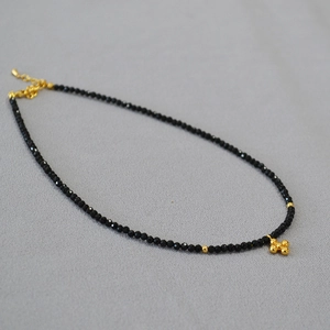 Dettaglio della collana di perline nere sfaccettate con sfere dorate e chiusura