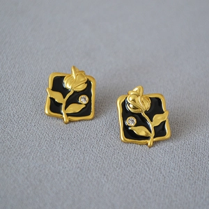 Detailed view of vintage gold rose earrings with black enamel inlay and zircon stone