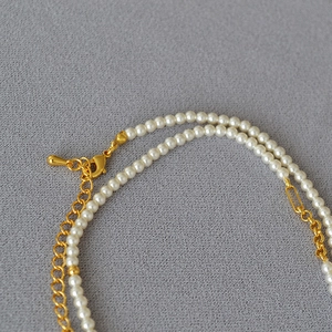 Detail of double-layer pearl necklace with gold lobster clasp and teardrop charm