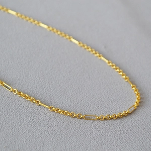 Macro shot of gold-plated brass necklace with alternating round and paperclip links