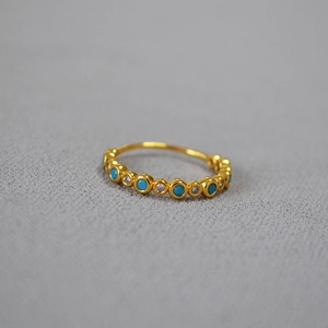 Macro shot of minimalist gold brass ring with turquoise and cubic zirconia inlay stones