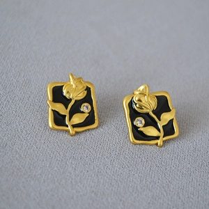 Detail of vintage gold brass square earrings with black enamel and rose floral relief