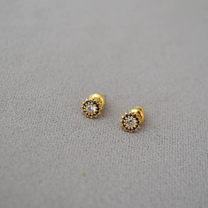 Close-up of small sunflower stud earrings with blue stones and a gold base