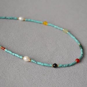 Detailed close-up of turquoise beads and freshwater pearls on a colorful necklace