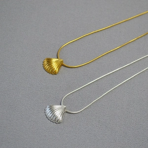 Detail of vintage shell pendants with sleek snake chains in gold and silver finishes
