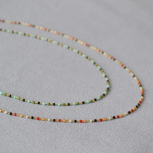 Makroaufnahme bunter Perlen an einer zarten Goldkette für eine Boho-Halskette
