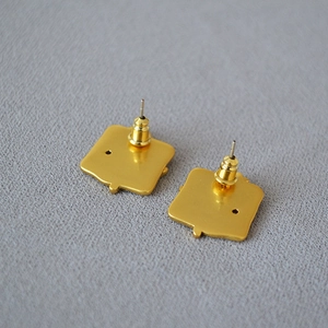 Macro view of gold-plated brass earring back with bullet clutch on grey fabric