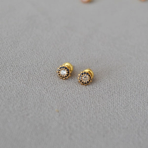 Close-up of flower stud earrings with a gold finish and vibrant blue stone petals