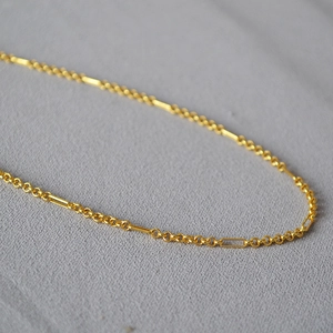Macro shot of 24K gold plated minimalist chain with interlinked round and bar charms