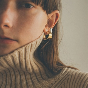 Close-up of irregular textured brass earrings with 925 silver needles on a model