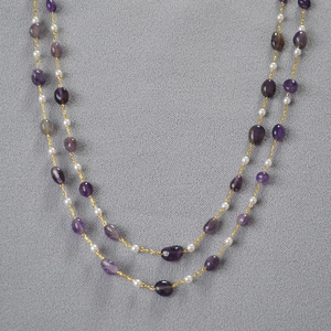 Detail of amethyst and pearl double layer necklace with gold chain and purple stones