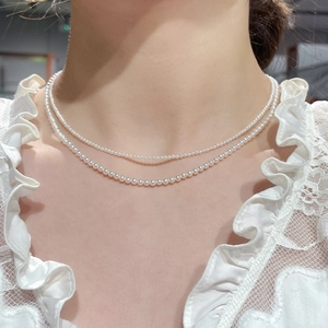 Nahaufnahme einer doppellagigen Perlenkette mit weißem Glanz und eleganter Spitze