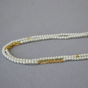 Detail of multi-layer pearl necklace showing double-row pearls and gold metal links