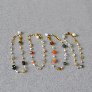 Detail of four handmade gold beaded bracelets with natural stones and white pearls