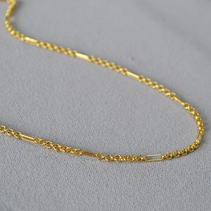 Macro shot of French minimalist gold plated necklace with delicate rings and bars