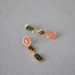 Detail of vintage three-stone drop earrings with pink, red and blue crystals in matte gold