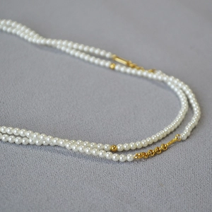 Close-up of double-layer small white pearl necklace with golden metal accents