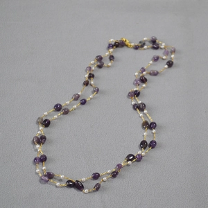 Detail of natural purple stones and white pearls on a double-layer long necklace