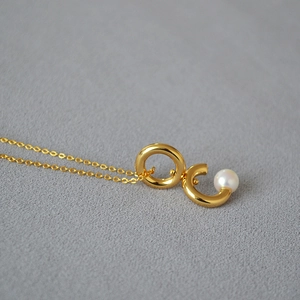 Élégant collier doré avec un pendentif à double anneau rotatif et une perle blanche fine