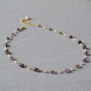 Close-up of handmade necklace with purple amethyst stones and white round pearls