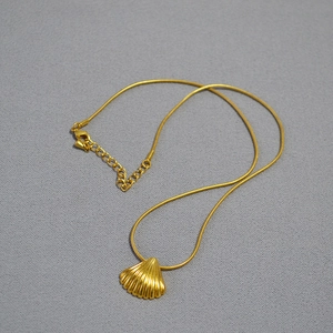 Detail of gold shell pendant on snake chain with adjustable clasp and lobster hook