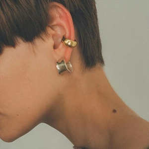 Close-up of a gold ear cuff and silver chunky irregular hoop earring on female model