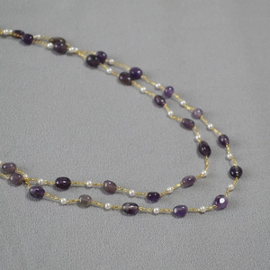 Close-up of double-layer necklace with natural purple gemstones and white beaded strands
