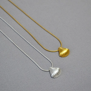 Detailed view of minimalist gold and silver shell pendants on sleek snake chains