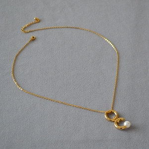 Collier doré élégant avec pendentif double anneau minimaliste et perle blanche délicate