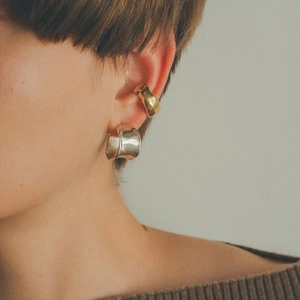 Detail of irregular gold ear cuff and silver hoop earring on model showing minimalist style