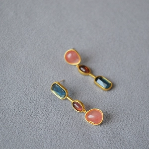 Detailed macro view of retro gold-tone drop earrings featuring colorful stone inlay