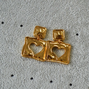 Detail of vintage gold square hollow heart earrings with hammered metal texture