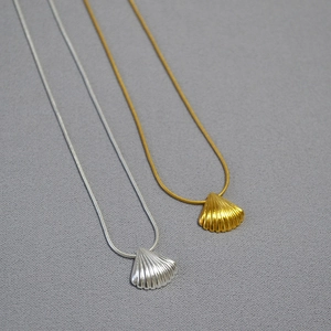 Detail of shell-shaped necklaces in gold and silver with fine snake chain textures