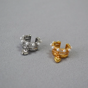 Detail of diamond quilted ear cuffs with pearls and heart pendants in gold and silver
