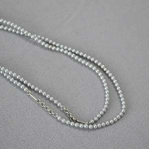 Close-up of double-layer grey pearl necklace with metallic silver links and extension chain