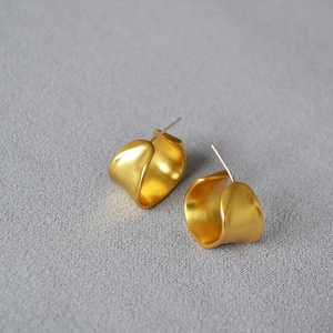 Macro detail of irregular gold-plated C-shaped earrings with a brushed matte texture
