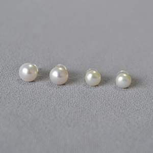 Detailed macro view of two pairs of round freshwater pearl studs with silicone backings